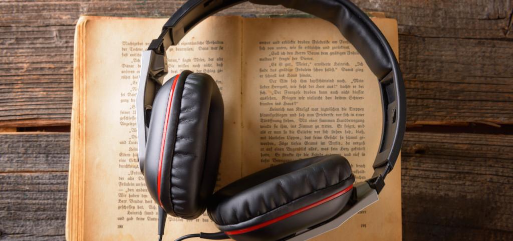 Auriculares encima de un libro representa audiobooks
