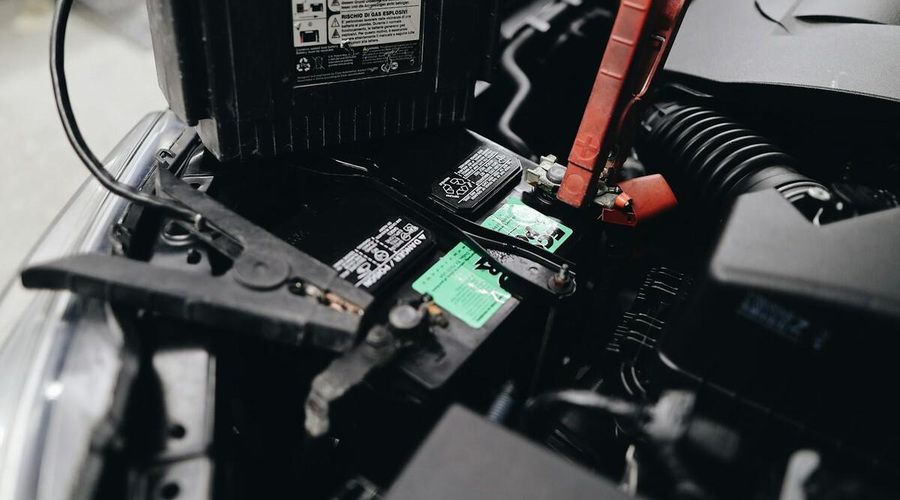 Primer plano de una batería de coche con pinzas de arranque conectadas a sus terminales