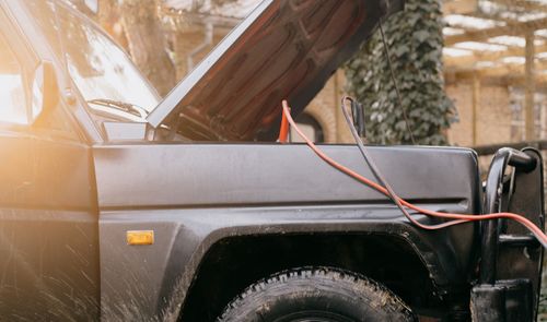 Coche todoterreno con el capó abierto y cables de arranque conectados para recuperar la batería
