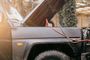 Coche todoterreno con el capó abierto y cables de arranque conectados para recuperar la batería