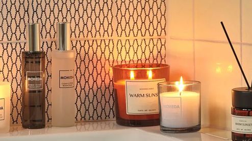 Velas aromáticas encendidas y ambientador con varillas decorando un baño con una iluminación cálida.