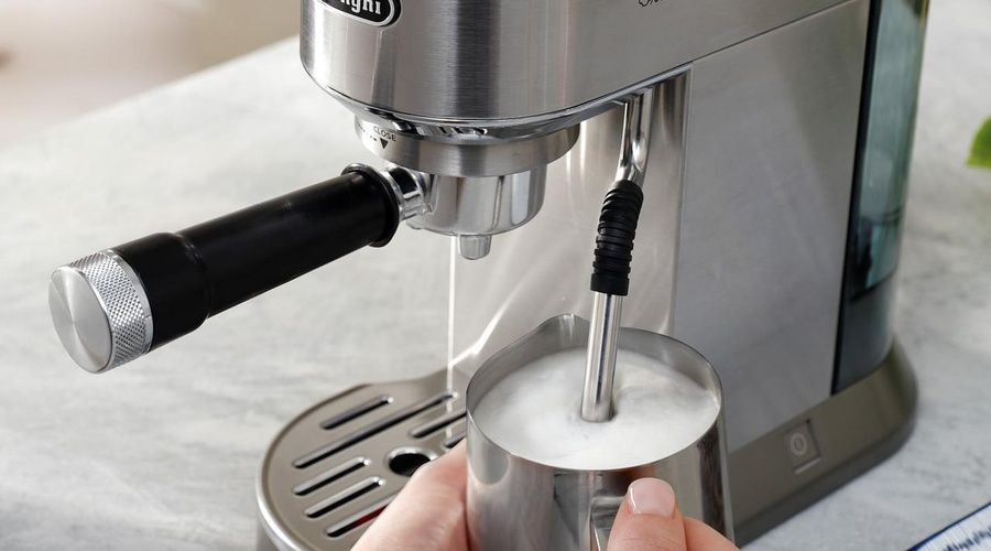 Vaporizador de la De'Longhi Dedica Duo espumando leche en una jarra metálica.