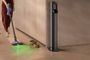 Persona utilizando una aspiradora Dyson V10 Konical para limpiar el suelo junto a un perro y varios restos de comida.