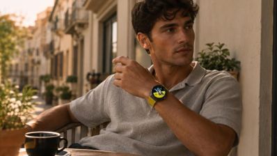 Hombre con un Huawei Watch GT 7 de correa amarilla mientras disfruta de un café en una terraza