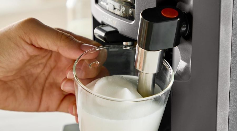 Detalle del espumador de leche manual de la KRUPS Harmony preparando espuma en un vaso de cristal