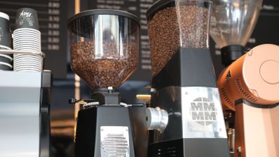 Molinillos de café profesionales con depósitos llenos de granos de café en una cafetería.