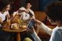 Tres personas sentadas en una cafetería utilizando sus smartphones POCO F9 para jugar en horizontal.