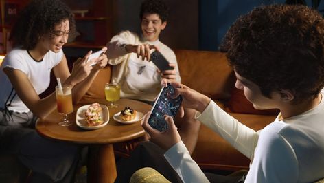 Tres personas sentadas en una cafetería utilizando sus smartphones POCO F9 para jugar en horizontal.