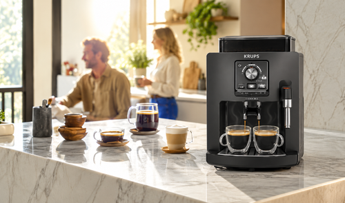 Cafetera superautomática KRUPS Harmony en color carbón preparando dos cafés sobre una encimera de mármol en una cocina moderna