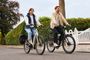 Dos personas circulando en bicicletas eléctricas negras por una calle residencial