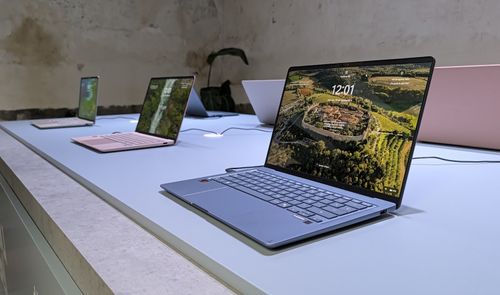 Varios portátiles ASUS Zenbook expuestos sobre una mesa, con un modelo plateado en primer plano y la pantalla encendida