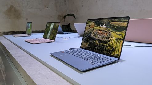 Varios portátiles ASUS Zenbook expuestos sobre una mesa, con un modelo plateado en primer plano y la pantalla encendida