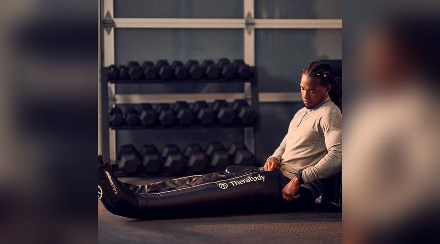 Deportista utilizando las botas de presoterapia Therabody JetBoots Prime mientras descansa después de entrenar en el gimnasio