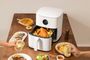Freidora de aire Xiaomi Smart Air Fryer 6.5L de color blanco con la cesta abierta y un pollo asado, rodeada de diferentes platos de comida