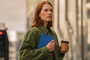 Mujer sosteniendo un reMarkable Paper Pro Move con funda azul mientras lleva un café en la mano.