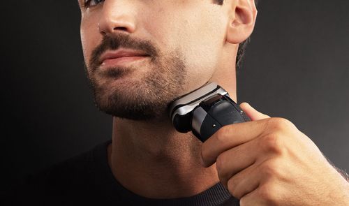 Hombre afeitándose el cuello con una afeitadora eléctrica inalámbrica Braun.