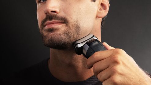 Hombre afeitándose el cuello con una afeitadora eléctrica inalámbrica Braun.