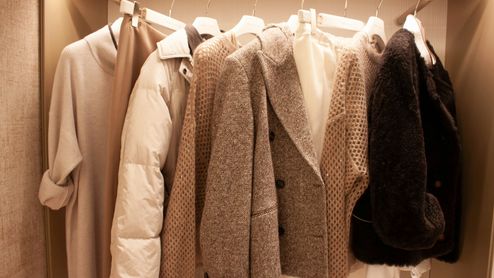 Armario con chaquetas, abrigos y prendas de punto en tonos beige, marrón y negro.