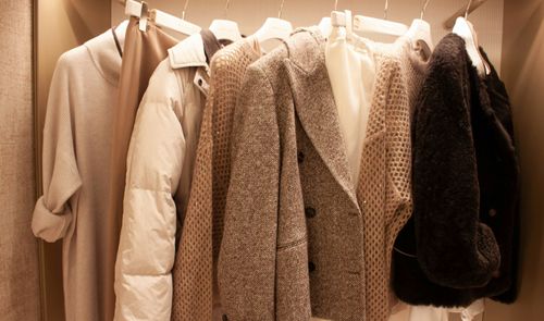 Armario con chaquetas, abrigos y prendas de punto en tonos beige, marrón y negro.