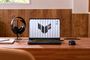 ASUS TUF Gaming F16 abierto sobre un escritorio de madera, junto a unos auriculares y un ratón.