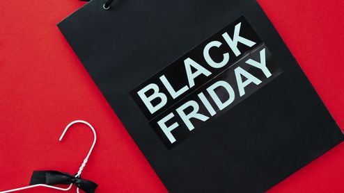 Bolsa negra con el texto Black Friday y una percha blanca sobre un fondo rojo.