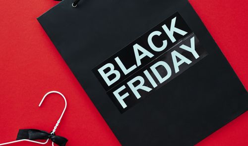 Bolsa negra con el texto Black Friday y una percha blanca sobre un fondo rojo.