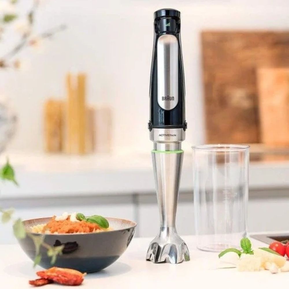 Batidora de mano Braun Minipimer 7 sobre una encimera de cocina junto a varios alimentos.