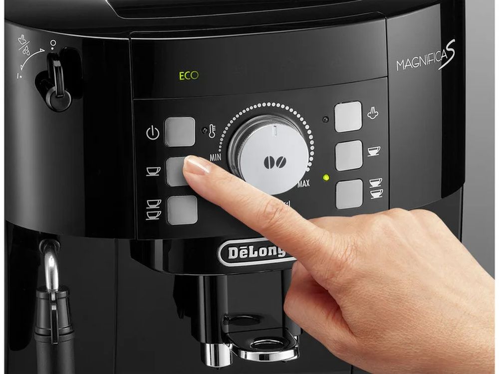 Mano pulsando un botón del panel frontal de una cafetera De’Longhi Magnifica S.