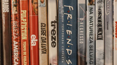 Colección de películas y series en DVD colocadas en una estantería, con los títulos visibles en los lomos.