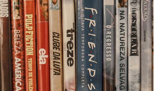 Colección de películas y series en DVD colocadas en una estantería, con los títulos visibles en los lomos.