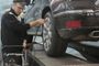 Mecánico inflando el neumático de un coche con una manguera conectada a un compresor en un taller.
