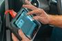 Una persona utiliza una tablet de diagnosis conectada por cable dentro de un coche.