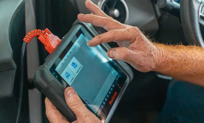 Una persona utiliza una tablet de diagnosis conectada por cable dentro de un coche.