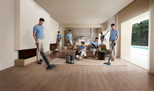 Montaje de un hombre utilizando la Dreame H15 Mix con distintos accesorios para limpiar el suelo, el sofá y los muebles de un salón.