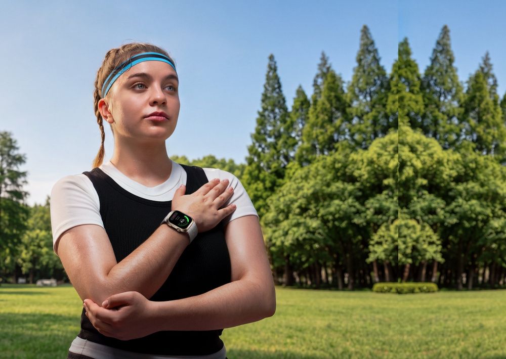 Mujer con ropa deportiva y un Huawei Watch D3 en la muñeca, con una mano apoyada sobre el pecho en un parque.