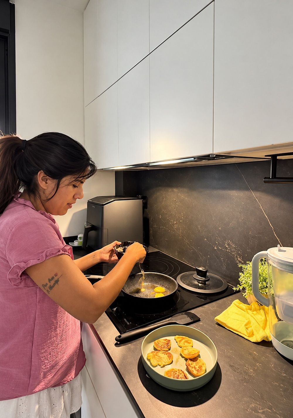 Isa Pantoja prepara unos huevos en su cocina, con muebles blancos y encimera negra.