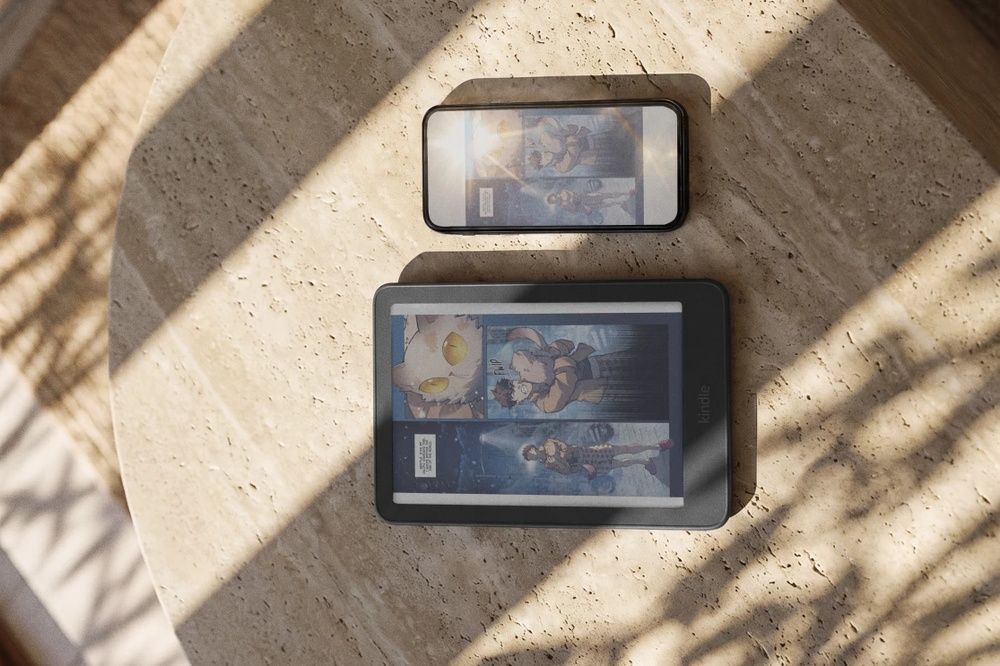 Kindle Colorsoft mostrando un cómic a color junto a un smartphone sobre una mesa.