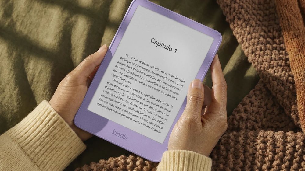 Persona sujetando un Kindle de color morado mientras lee un libro.