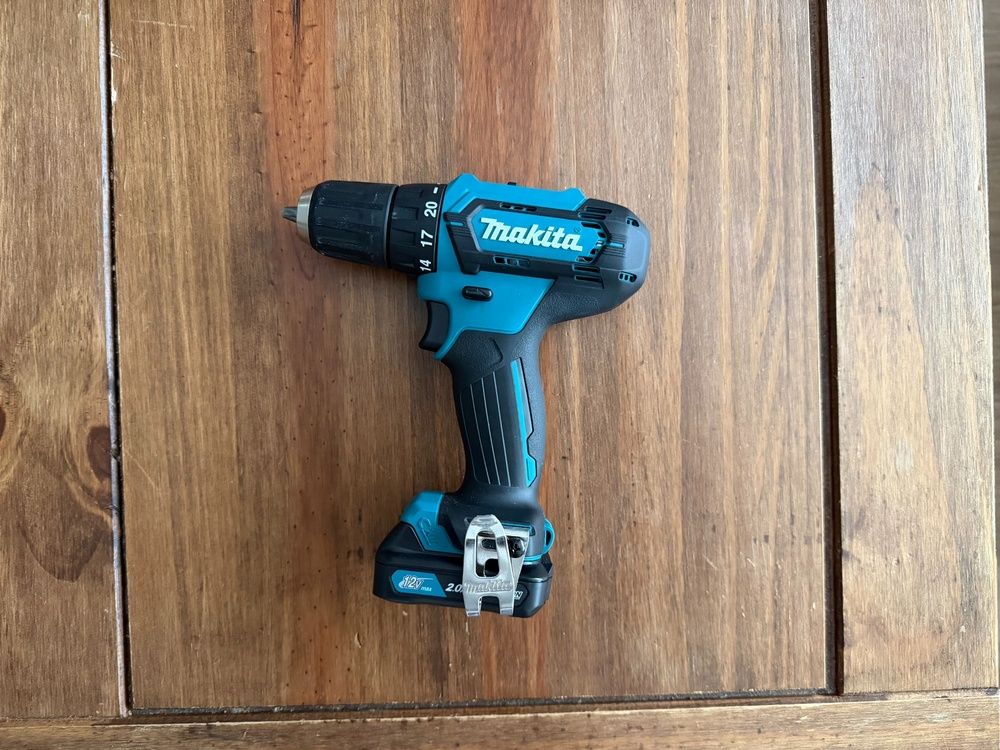 Taladro inalámbrico Makita con batería instalada sobre una superficie de madera, visto desde arriba.