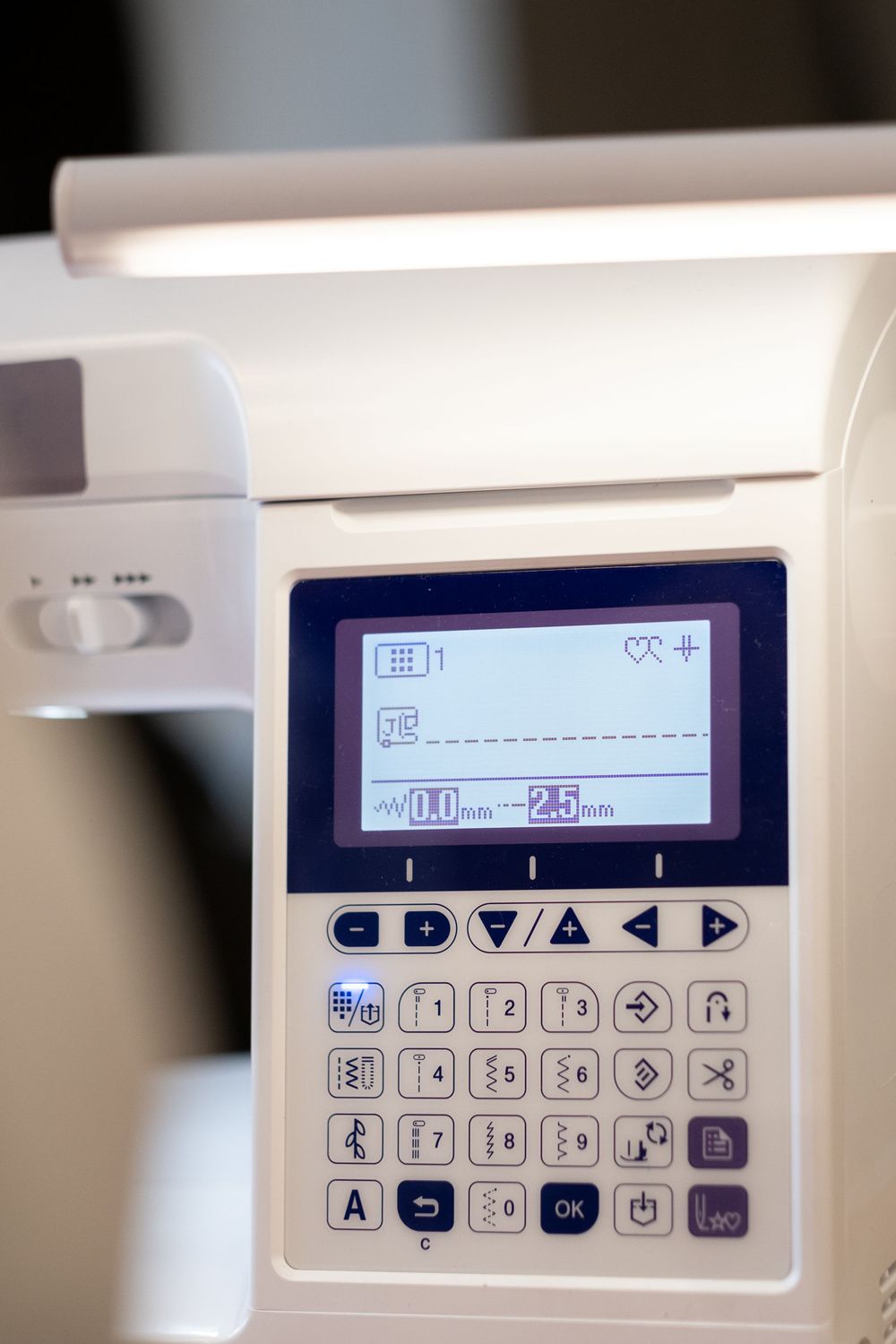 Pantalla y botones de una máquina de coser electrónica para seleccionar y ajustar las puntadas.