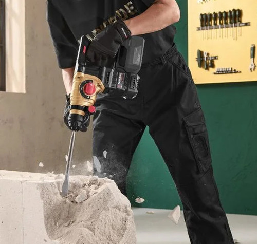 Primer plano de un martillo perforador Parkside negro y dorado, utilizado con un cincel para romper un bloque de obra.