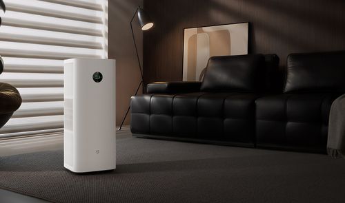 Mijia Smart Air Purifier 6 Plus blanco junto a una ventana y un sofá negro en un salón.