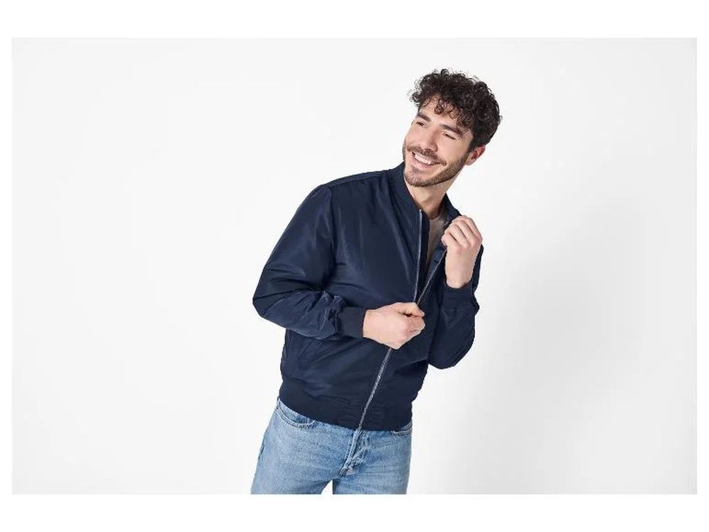 Hombre con cazadora bomber azul marino y pantalones vaqueros