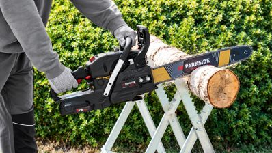 Persona cortando un tronco de madera con una motosierra a batería Parkside Performance.