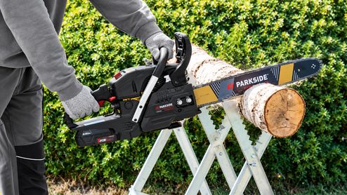 Persona cortando un tronco de madera con una motosierra a batería Parkside Performance.