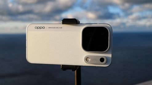 Parte trasera de un móvil OPPO colocado en horizontal sobre un soporte, con el mar de fondo.