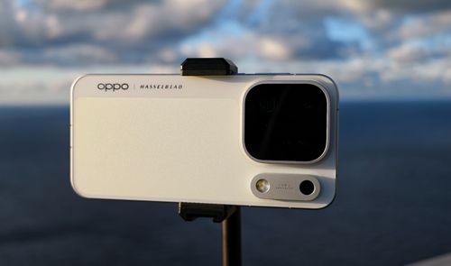 Parte trasera de un móvil OPPO colocado en horizontal sobre un soporte, con el mar de fondo.