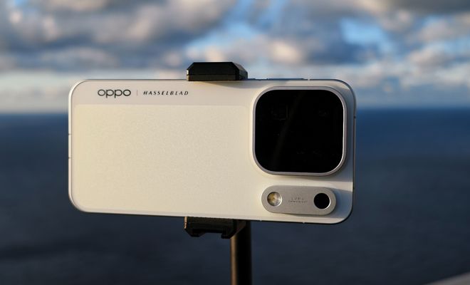 Parte trasera de un móvil OPPO colocado en horizontal sobre un soporte, con el mar de fondo.