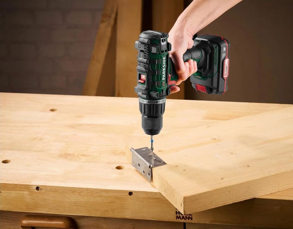 Taladro atornillador Parkside fijando una escuadra metálica entre dos piezas de madera.