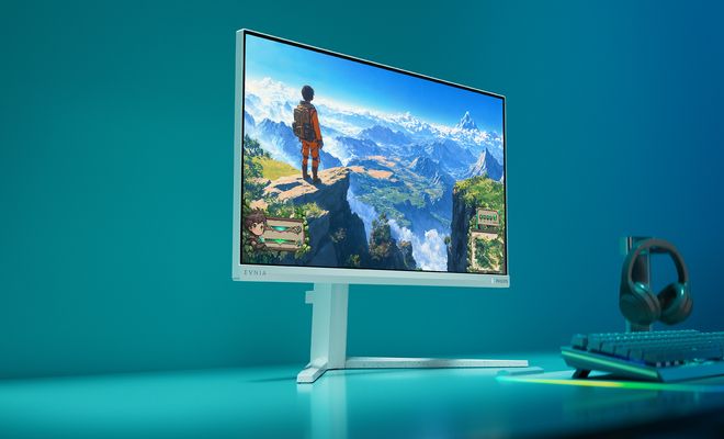 Monitor Philips Evnia 24M2N3201P blanco sobre un escritorio con iluminación azul, junto a un teclado y unos auriculares.